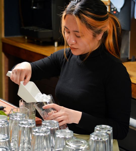 Mitarbeiterin von umaii ramen restaurant bereitet Getränke hinter der Bar zu