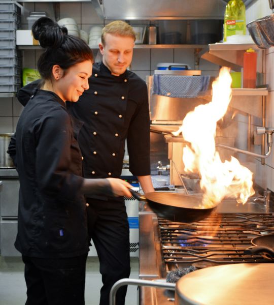 zwei Mitarbeiter in der Küche von umaii Ramen restaurant kochen mit Flamme am Herd